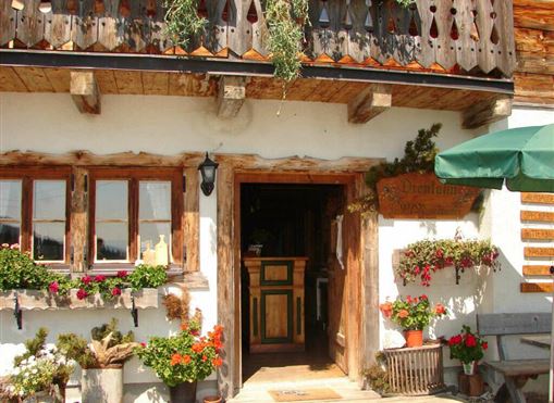 Ein rustikales Gebäude mit Holzverkleidung und einem einladenden Eingang. Bunte Blumenblüten schmücken die Fenster und den Außenbereich.