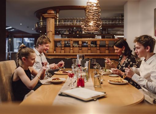 Eine Familie sitzt zusammen an einem Tisch in einem Restaurant. Alle genießen ihr Essen und haben eine angenehme Zeit miteinander.