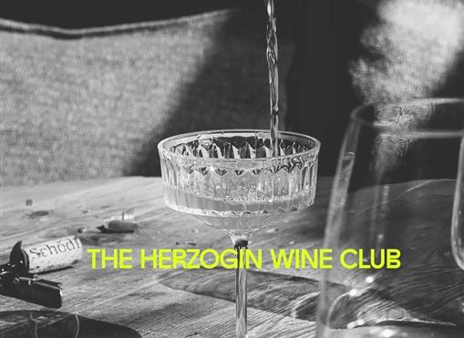 Ein elegantes Glas wird mit Wein gefüllt. Im Hintergrund sind unscharfe Gläser und eine gemütliche Umgebung sichtbar.