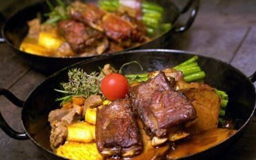 Zwei Schalen mit leckerem Fleisch, Gemüse und einer Tomate. Das Gericht sieht herzhaft und einladend aus.