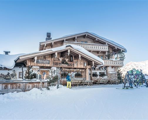A charming log cabin in the snow with traditional wooden design. Surrounded by a wintry landscape and ski wagons.